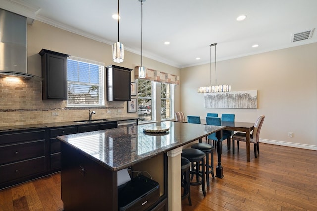 1005 Highknoll Ln, Georgetown, TX 78628 - kitchen with a sink, wall chimney range hood, a kitchen breakfast bar, decorative backsplash, and ornamental molding