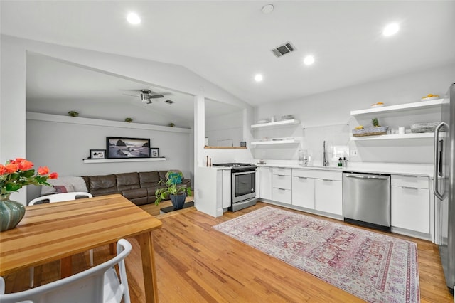 kitchen with vaulted ceiling, sink, white cabinetry, light hardwood / wood-style floors, and stainless steel appliances