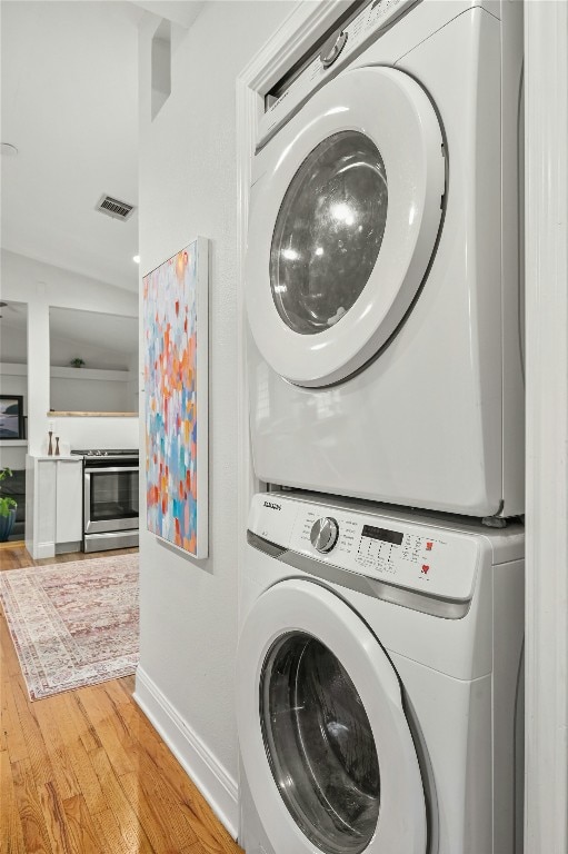 laundry area with hardwood / wood-style flooring and stacked washer / drying machine