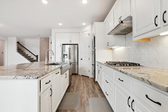 kitchen with stainless steel appliances, recessed lighting, a sink, wood finished floors, and under cabinet range hood