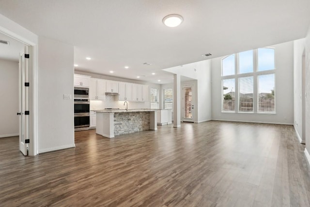 unfurnished living room featuring plenty of natural light, sink, and dark hardwood / wood-style floors