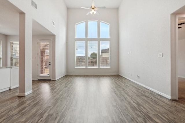 unfurnished living room with a high ceiling, dark hardwood / wood-style floors, and ceiling fan