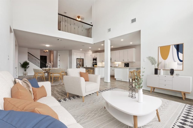 living area featuring light wood-type flooring, visible vents, recessed lighting, and stairs