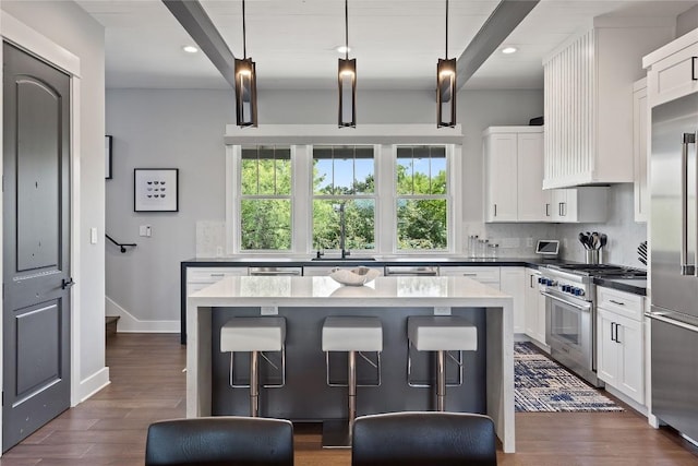 kitchen with hanging light fixtures, high end appliances, white cabinets, and decorative backsplash