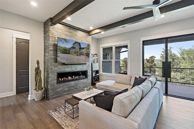 living room featuring beamed ceiling, a stone fireplace, and dark hardwood / wood-style flooring