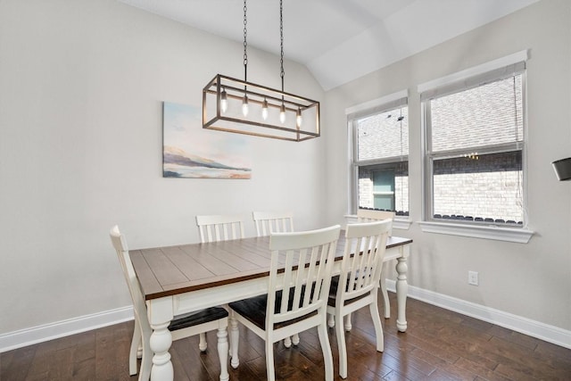 dining area with dark wood-type flooring and vaulted ceiling