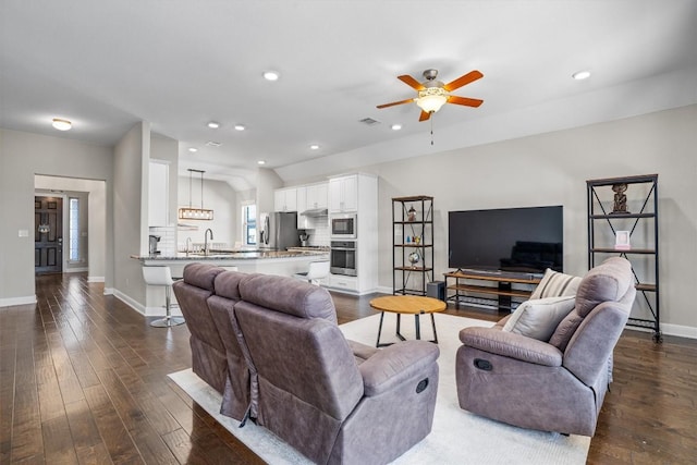 living room featuring dark hardwood / wood-style flooring, sink, vaulted ceiling, and ceiling fan