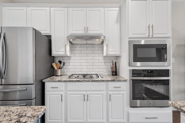 kitchen with tasteful backsplash, stainless steel appliances, light stone countertops, and white cabinets