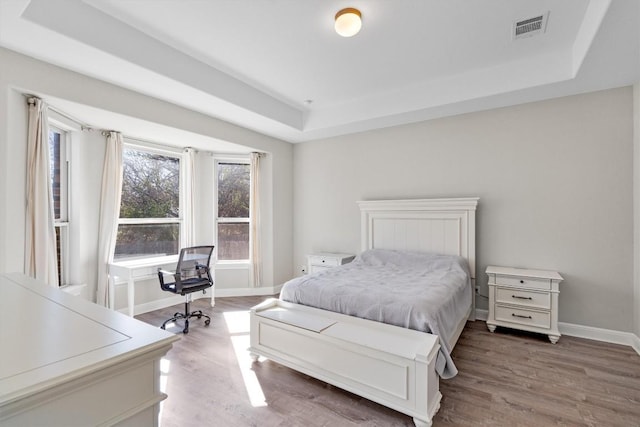 bedroom featuring hardwood / wood-style flooring and a tray ceiling