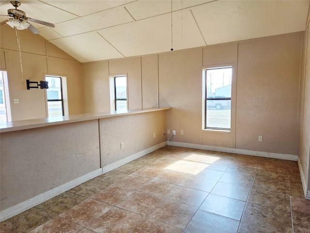 empty room featuring ceiling fan, vaulted ceiling, tile patterned floors, and a healthy amount of sunlight