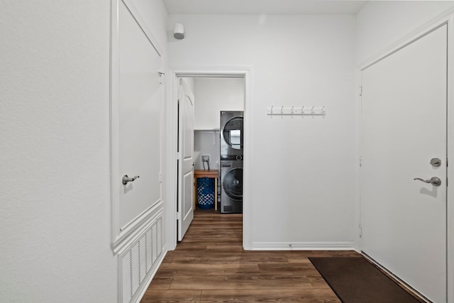 corridor with stacked washer and clothes dryer and dark hardwood / wood-style floors