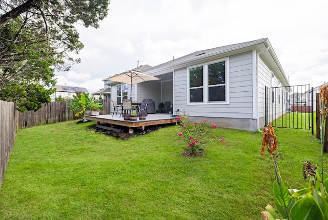 rear view of property featuring a wooden deck and a lawn