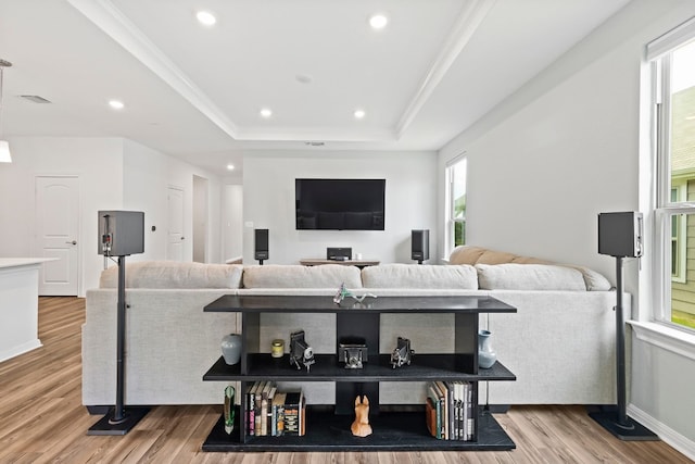 living room featuring crown molding, a tray ceiling, and light hardwood / wood-style flooring