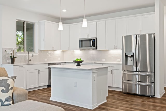 kitchen with sink, white cabinetry, stainless steel appliances, a center island, and decorative light fixtures