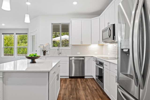 kitchen featuring sink, white cabinetry, decorative light fixtures, appliances with stainless steel finishes, and backsplash