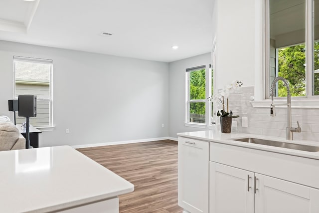 kitchen featuring white cabinetry, sink, tasteful backsplash, and light hardwood / wood-style floors