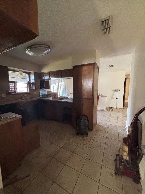 kitchen with light tile patterned floors, kitchen peninsula, and a textured ceiling