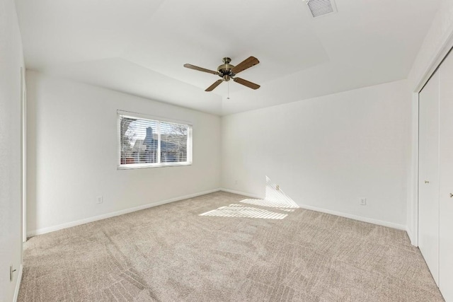 carpeted spare room featuring ceiling fan and a raised ceiling