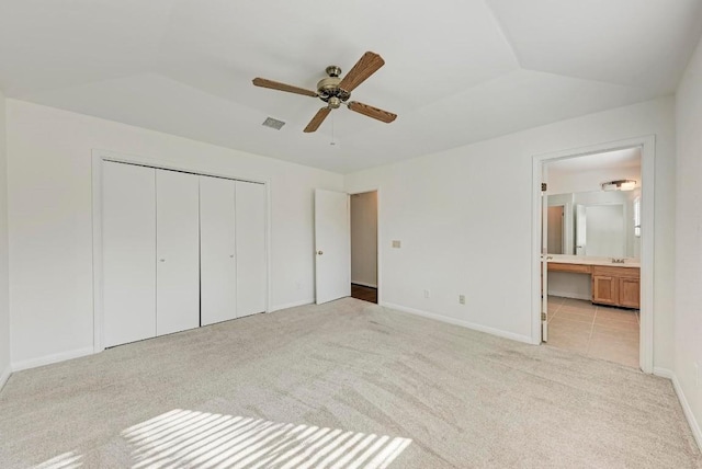 unfurnished bedroom featuring vaulted ceiling, ceiling fan, light carpet, ensuite bath, and a closet