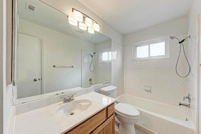 full bathroom featuring vanity, tiled shower / bath, and toilet