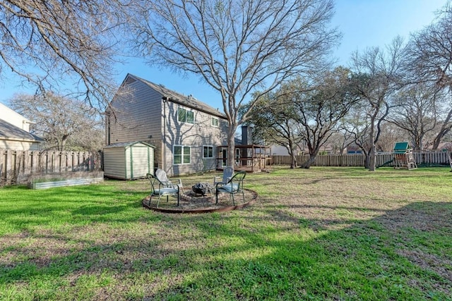 view of yard with a storage shed, a playground, and a fire pit