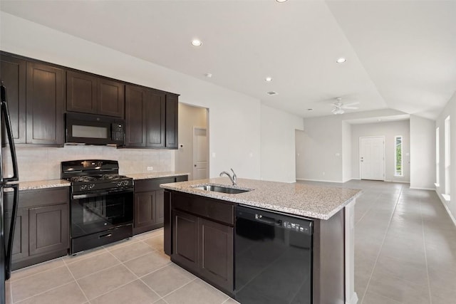 kitchen with tasteful backsplash, sink, black appliances, dark brown cabinets, and a center island with sink