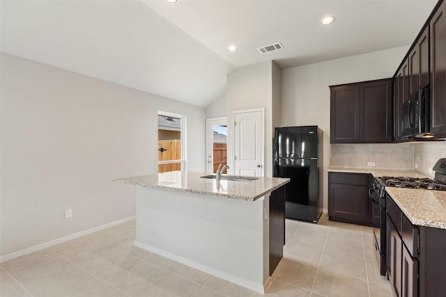 kitchen with sink, a center island with sink, light stone counters, and black appliances