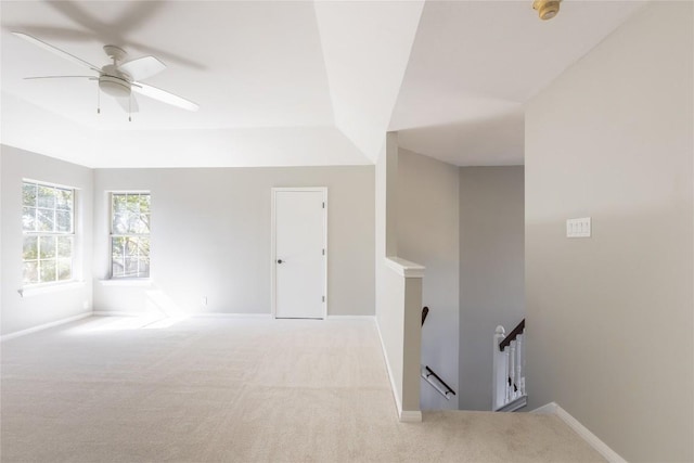 carpeted empty room with ceiling fan and a tray ceiling