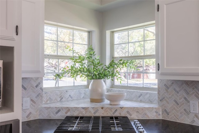 details with stainless steel gas stovetop, stone countertops, and white cabinets