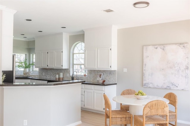 kitchen featuring tasteful backsplash, white cabinetry, plenty of natural light, and kitchen peninsula