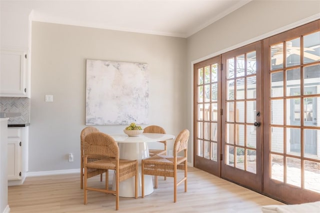 dining space with french doors, crown molding, and light hardwood / wood-style flooring