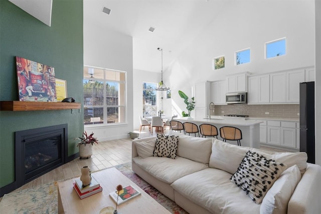 living room with light hardwood / wood-style floors, sink, and a high ceiling