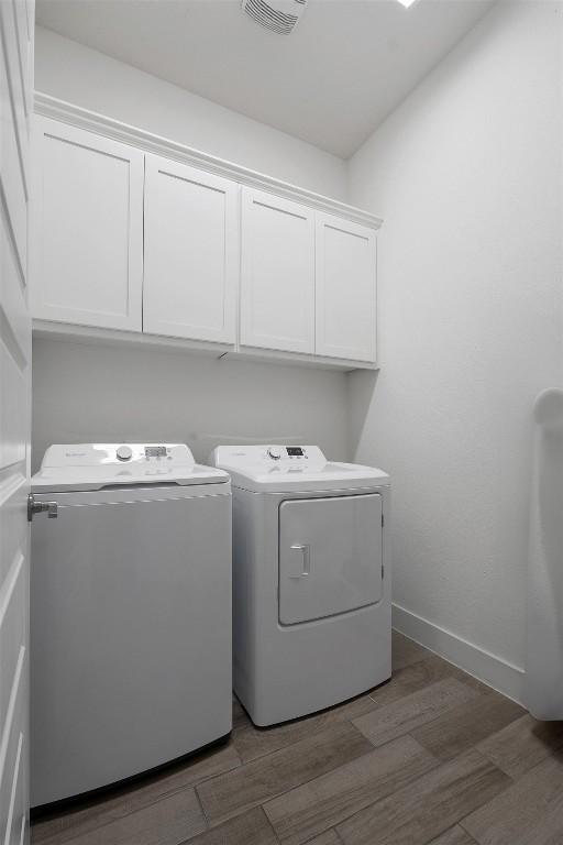 laundry area featuring dark wood-type flooring, cabinets, and separate washer and dryer