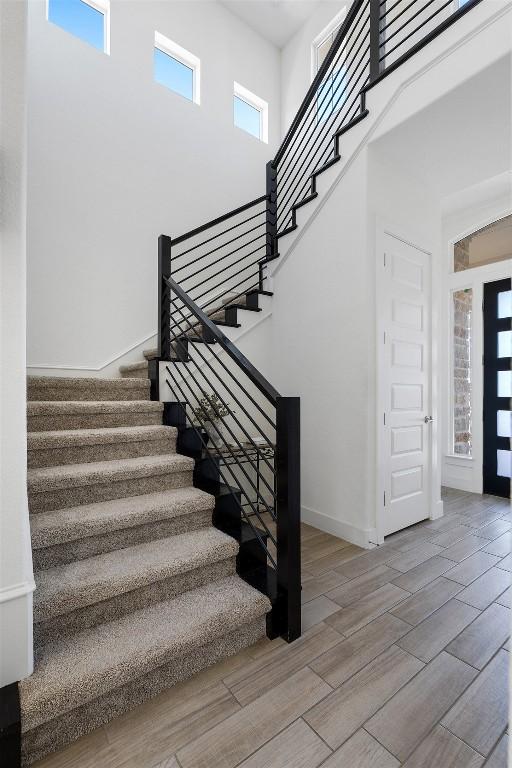 staircase with wood-type flooring and a high ceiling