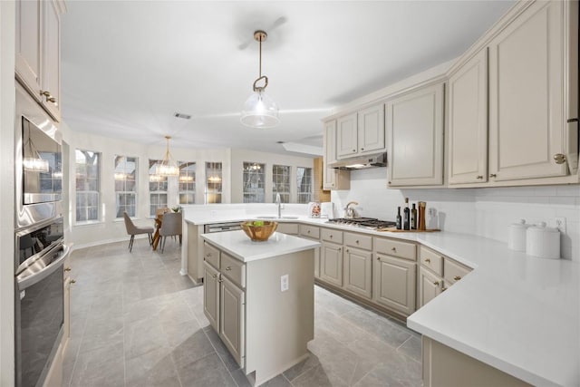 kitchen with sink, decorative light fixtures, a kitchen island, stainless steel appliances, and decorative backsplash