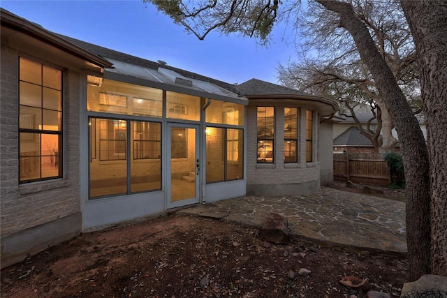 back house at dusk featuring a patio