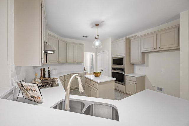 kitchen featuring pendant lighting, appliances with stainless steel finishes, sink, and cream cabinetry