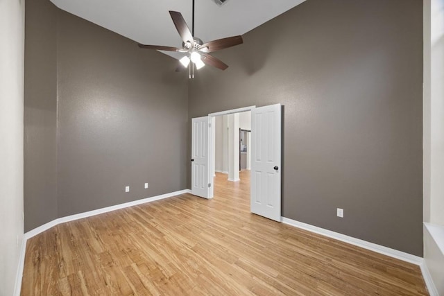 unfurnished bedroom featuring light hardwood / wood-style flooring, ceiling fan, and a high ceiling