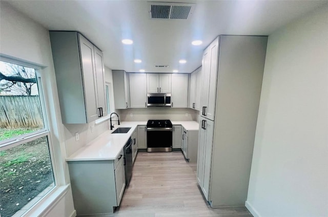 kitchen featuring stove, sink, light hardwood / wood-style floors, and dishwasher