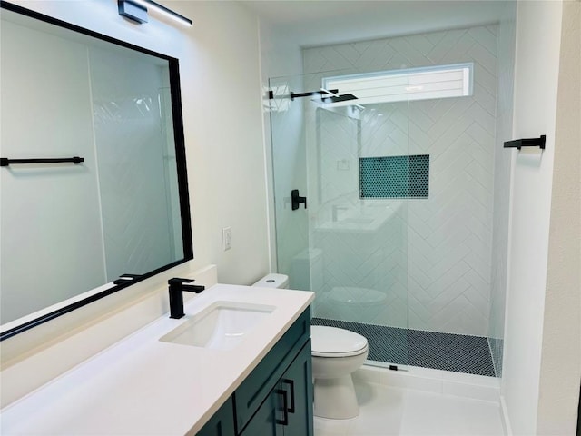 bathroom with vanity, toilet, and tiled shower