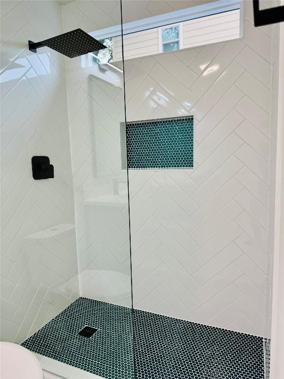 bathroom featuring tiled shower and toilet