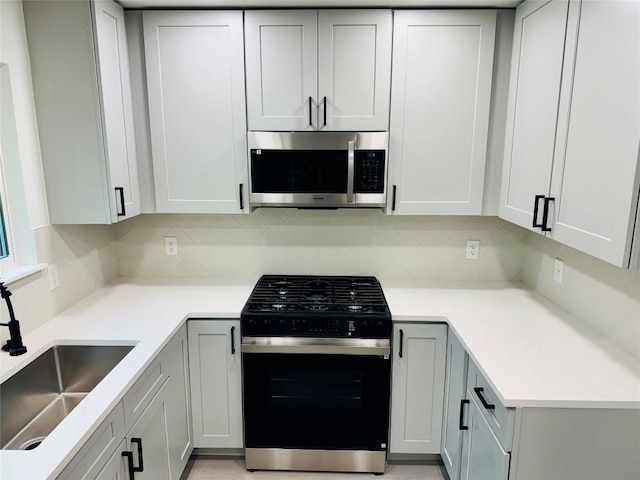 kitchen with sink, backsplash, gray cabinets, and range with gas stovetop