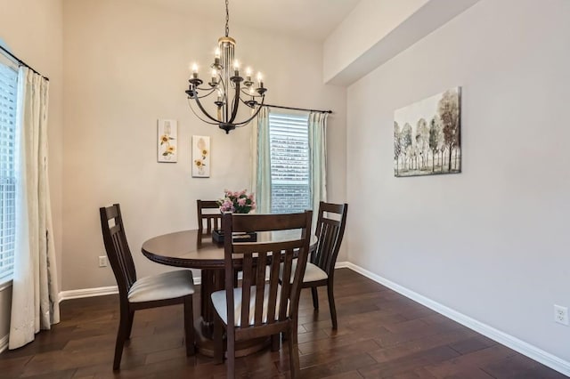 dining space with dark wood-style floors, a notable chandelier, and baseboards