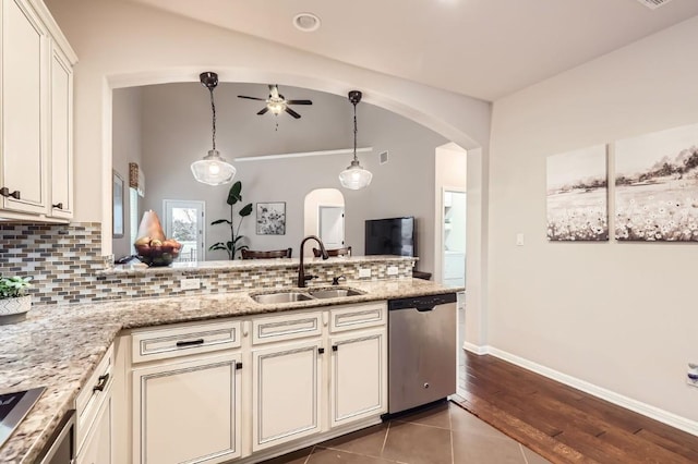 kitchen with a sink, arched walkways, light stone counters, and stainless steel dishwasher