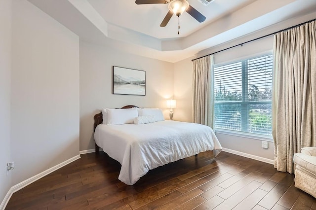 bedroom featuring a ceiling fan, baseboards, a raised ceiling, and dark wood-type flooring