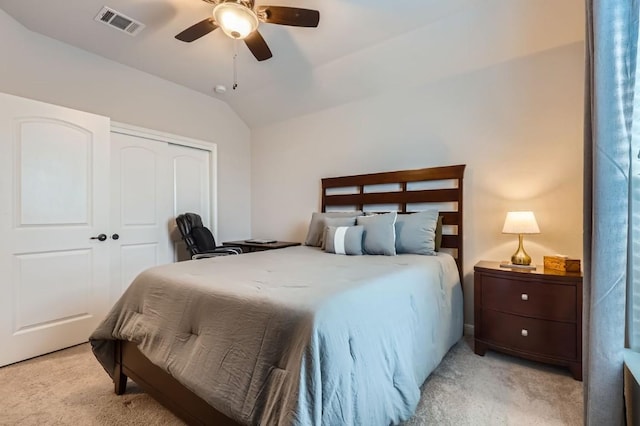 bedroom with lofted ceiling, a closet, light colored carpet, and visible vents