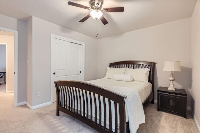 bedroom with light carpet, ceiling fan, baseboards, and a closet