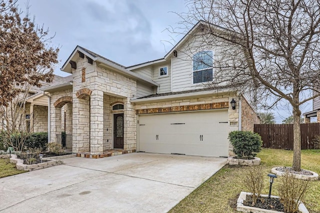 view of front of home featuring driveway, stone siding, an attached garage, and fence