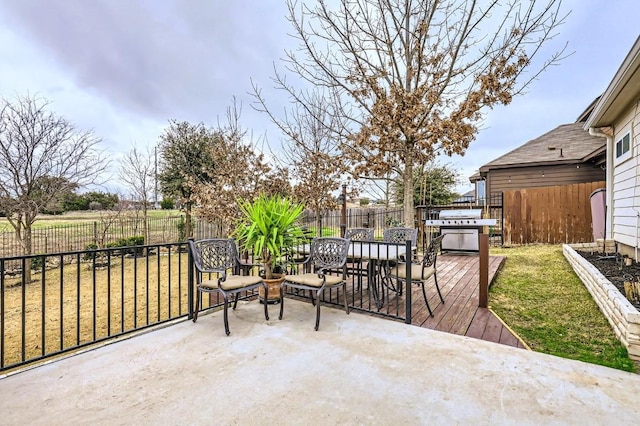 wooden terrace with outdoor dining space, a grill, a fenced backyard, and a patio