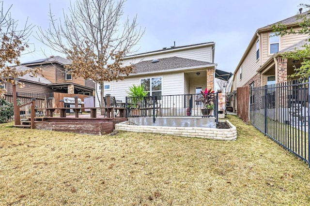 rear view of property featuring a deck, a lawn, and fence